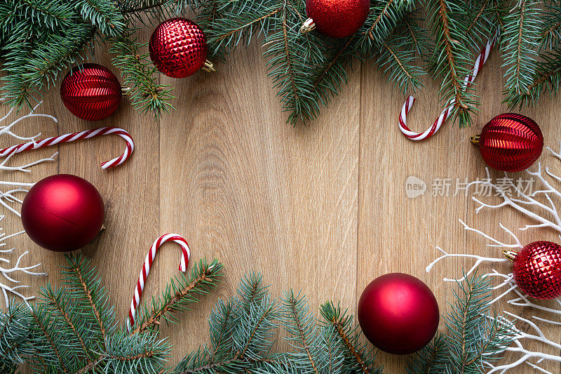 圣诞平面构图与复制空间在木制背景。喜庆的红色小玩意装饰，棒棒糖装饰，冷杉树枝装饰。