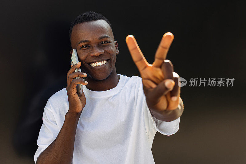 快乐的年轻非裔美国人用智能手机微笑