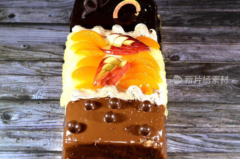 生日蛋糕三种不同的海绵奶油蛋糕庆祝，榛子巧克力涂抹，黑巧克力，焦糖，打发香草奶油，菠萝片，苹果，桃子和坚果