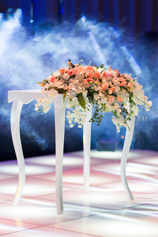 婚礼桌上放着鲜花，舞台上飘着烟雾
