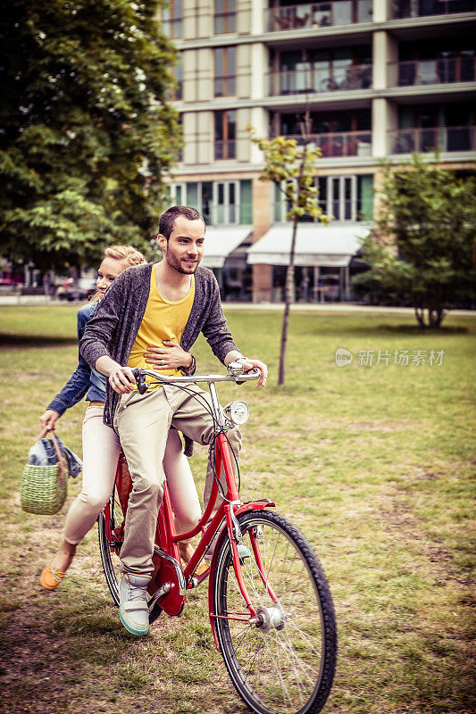 一对年轻情侣在城市公园里一起骑车