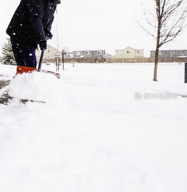 在暴风雪中从车道上铲雪的人