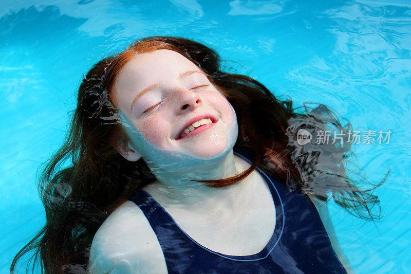 小女孩在蓝色的水池里嬉戏，淹没在水中