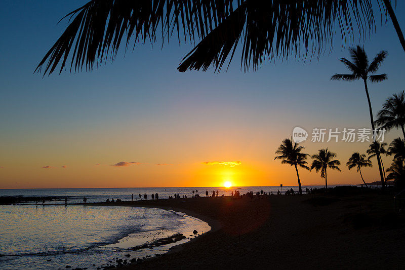 人们聚集在夏威夷考艾岛热带度假海滩日落