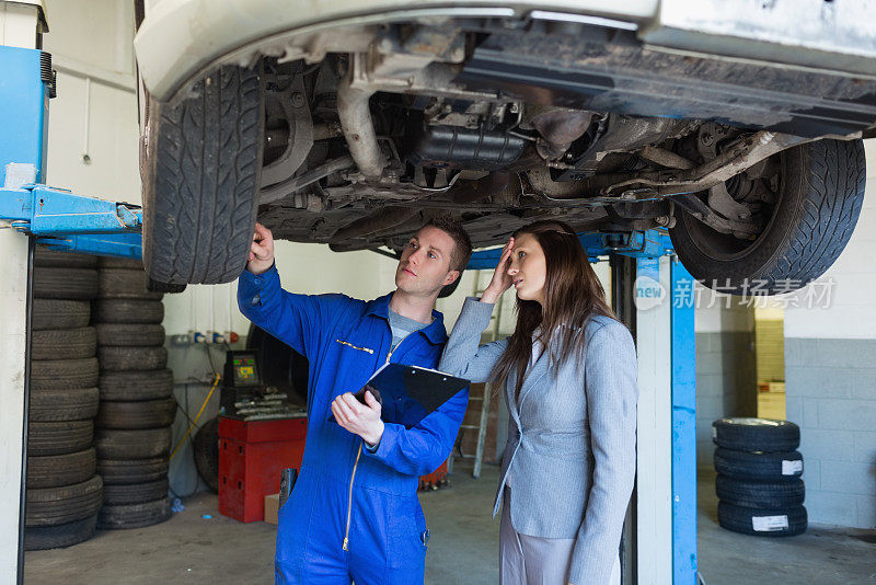 汽车修理工和妇女检查汽车轮胎