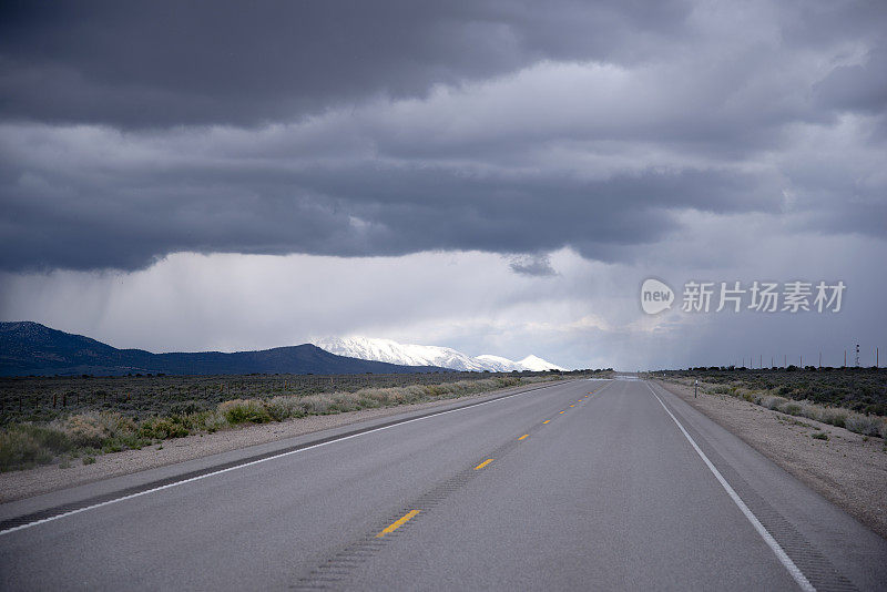 道路延伸到地平线，暴风雨的天空和雪山