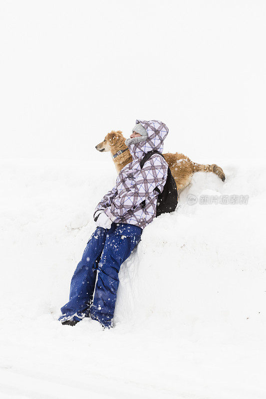 一个女人在下雪的时候和她的狗玩