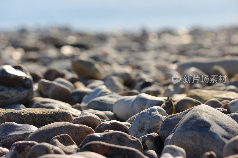 阳光明媚的海滩上的大卵石图像，聚焦前景