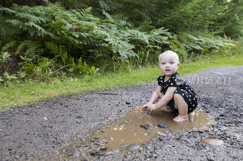 可爱的宝宝在森林里的雨水水坑里玩耍
