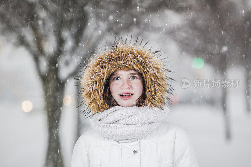 雪下穿着白色夹克的漂亮少女