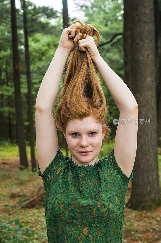 一个自然的红发少年的肖像在秋天拿着头发