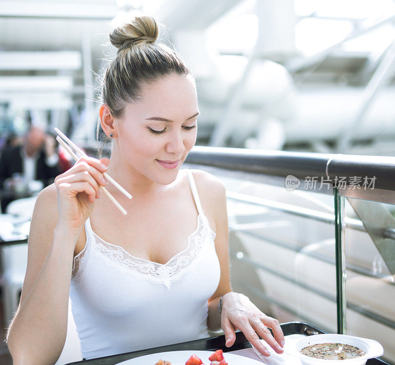 在美食广场吃寿司的女人