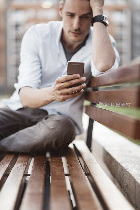 一名年轻人在一个阳光明媚的日子里在公园里使用智能手机