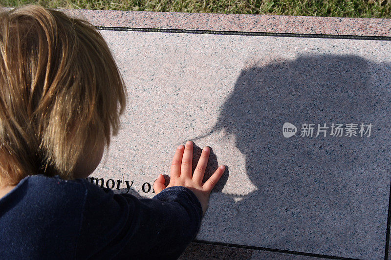 小女孩靠在墓地的一块墓碑上