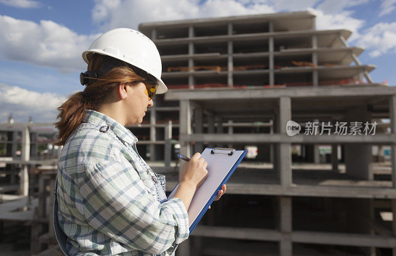 女建筑师在建筑工地的剪贴板上写字