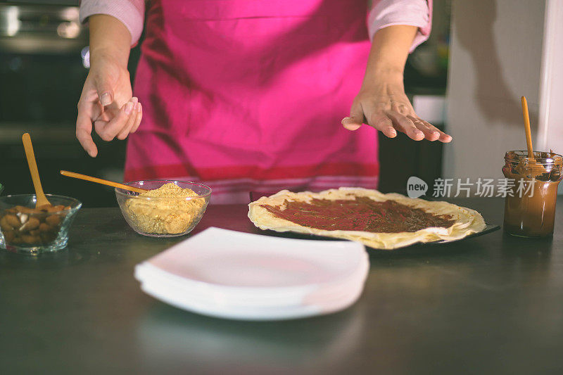 女孩倒了一勺面团做煎饼。在家做煎饼。