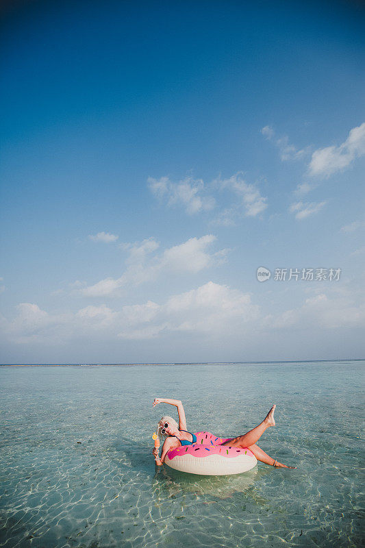 性感的女人浮在水上，有鸡尾酒时间在海洋，马尔代夫