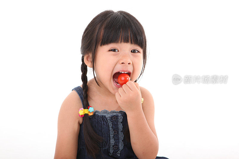 快乐的女孩吃着新鲜的樱桃番茄