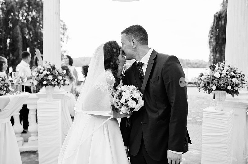 一对新婚夫妇在白色拱门下拍照。