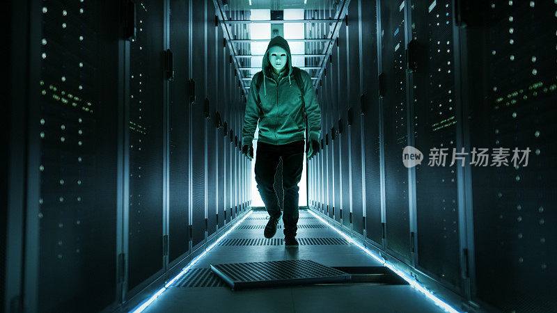 戴着面罩的黑客穿过工作数据中心，中间有一个开放的地板舱口。