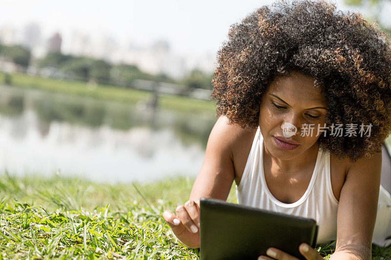 非洲妇女在公园里使用数字平板电脑