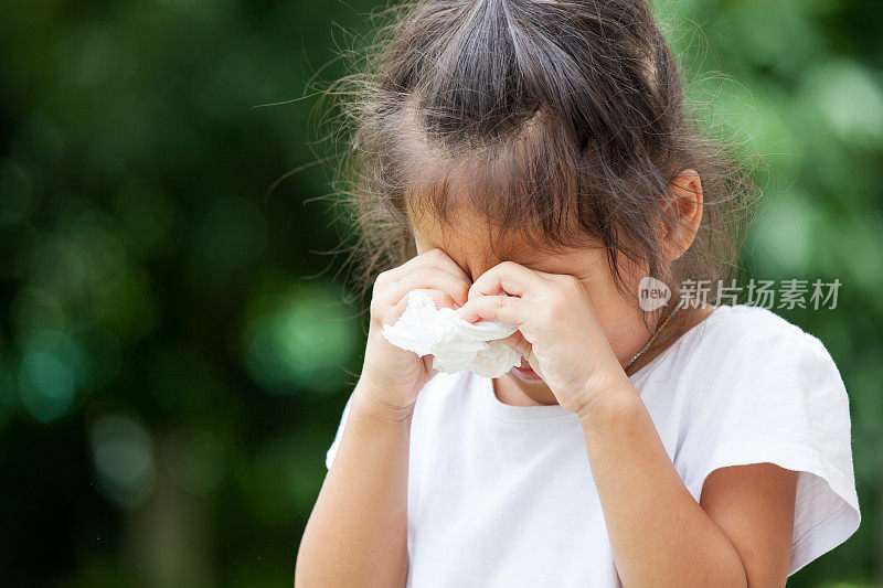 伤心的亚洲小女孩哭着，手里拿着纸巾