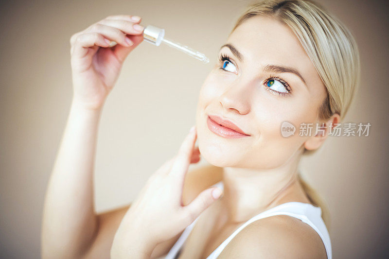 女人优雅的化妆应用血清治疗。副本的空间。
