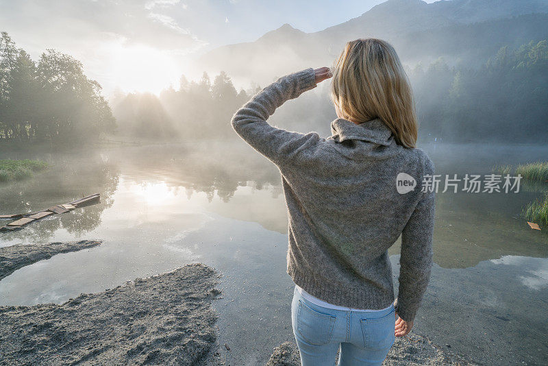 日出时分，年轻女子在湖边凝望大自然