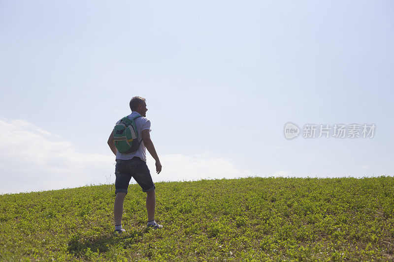 成年徒步旅行者在乡间的自然环境下，越过山的地平线