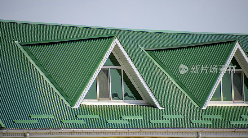 有塑料窗户和波纹板的绿色屋顶的房子。绿色屋顶波纹金属型材和塑料窗户。