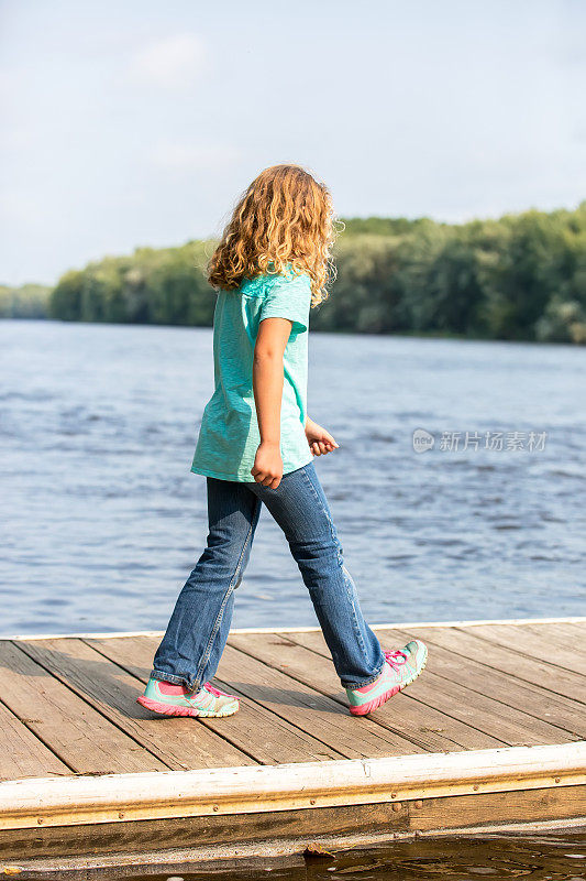走在密西西比河木码头上的年轻女孩