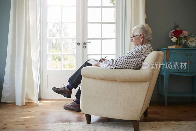 老人坐在扶手椅上做填字游戏，侧视图