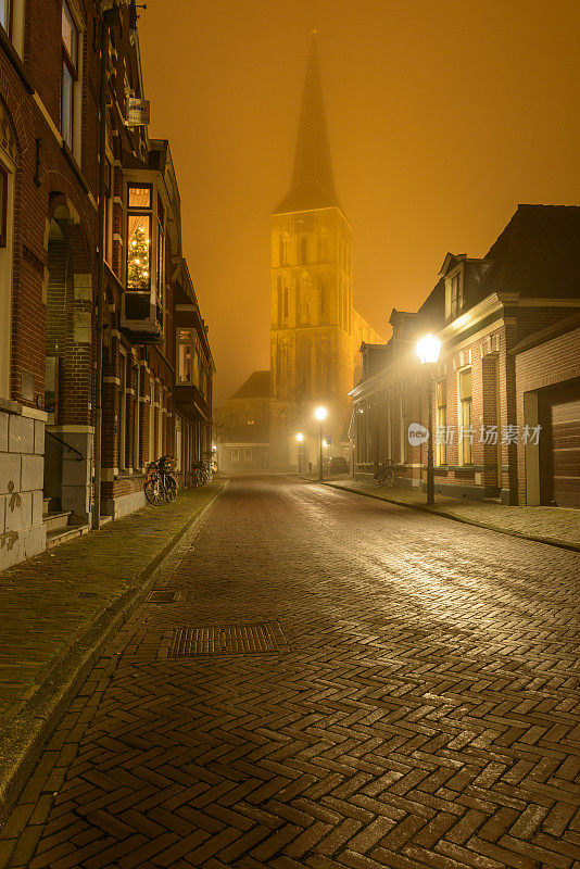 在一个雾蒙蒙的冬天夜晚，在Kampen的Bovenkerk教堂的夜间街景