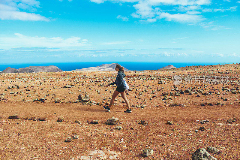 年轻女子徒步旅行与全景火山