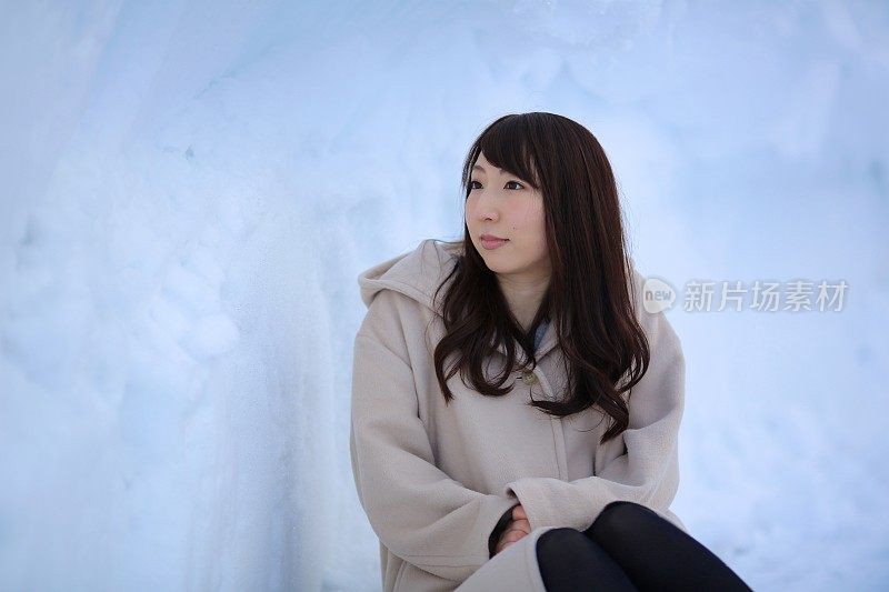 年轻女子坐在雪洞里