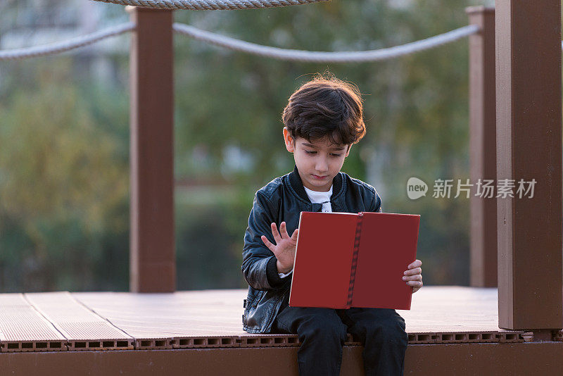 快乐的男孩坐在公园里看书