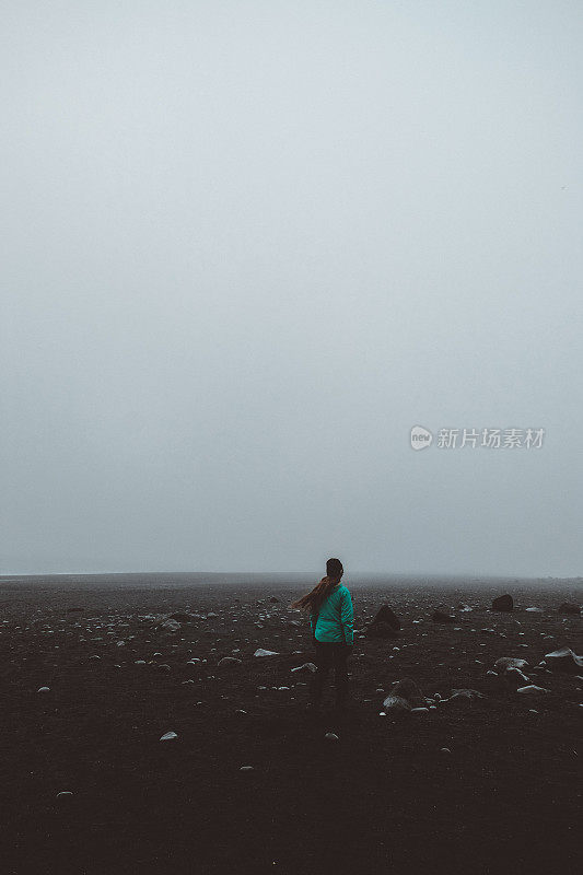 一名女子在冰岛黑沙滩的迷雾中奔跑