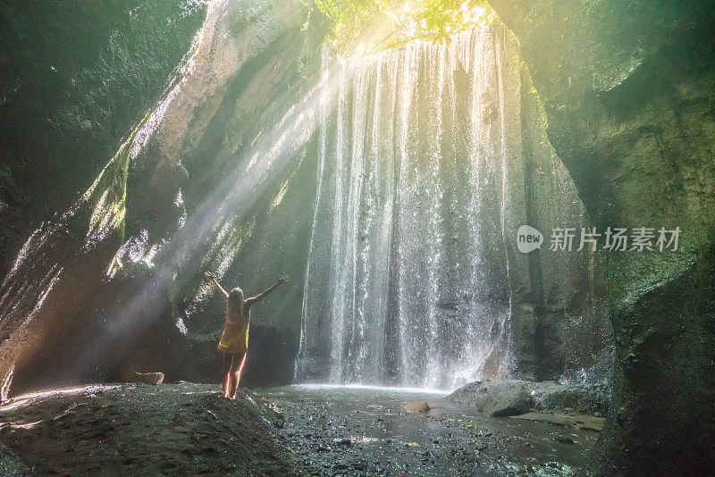 在巴厘岛的热带雨林中，旅行的年轻女子张开双臂拥抱大自然的美丽。人们以自然为旅游理念。