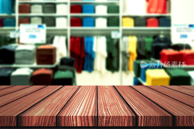 木制的桌子与模糊的背景休闲精品店，衬衫品牌outlet或彩色服装店的产品展示蒙太奇。以时尚产品零售业务为网络营销背景。