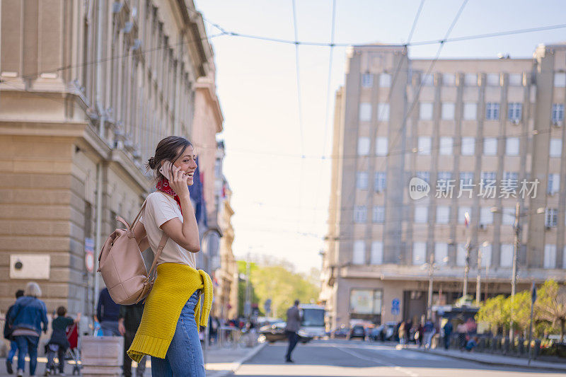 一名年轻女子正带着她的智能手机走在城市的路上