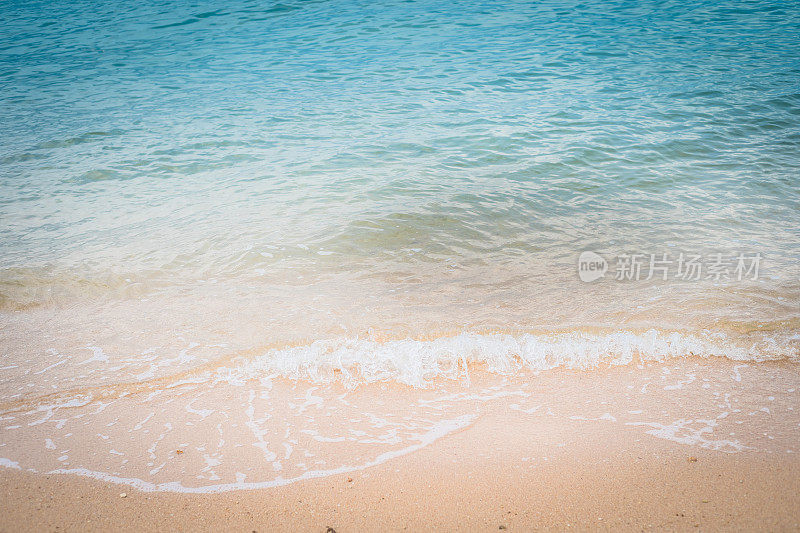 柔软的蓝色海浪在沙滩上。背景