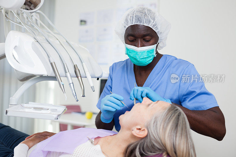 成年女性病人坐在牙科椅上。牙医正在治疗一位女病人