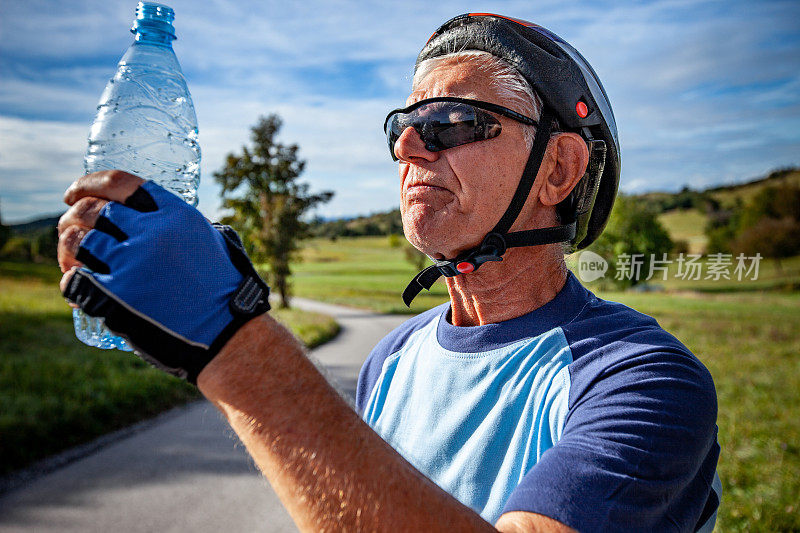 骑自行车的老人拿着水瓶
