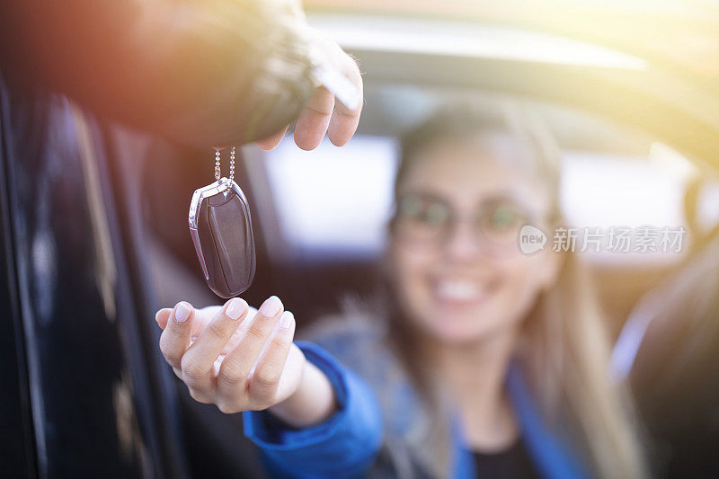 快乐的年轻女子展示了她第一辆车的钥匙