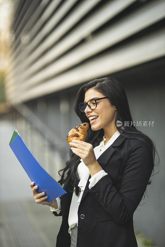 女商人一边吃牛角面包一边工作