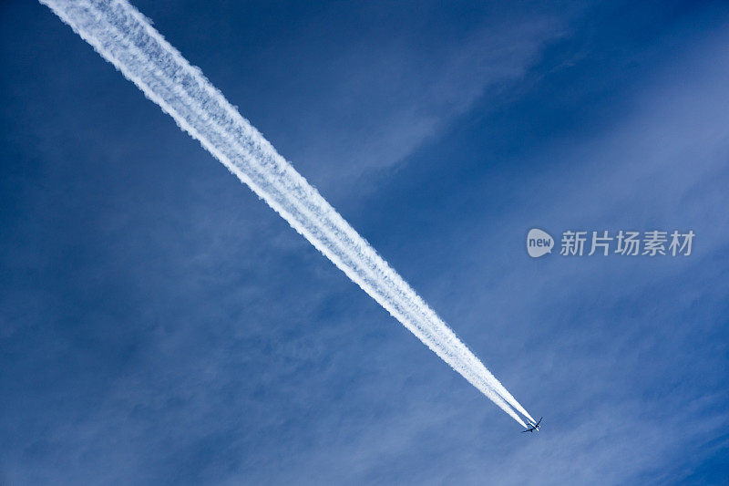 飞机在深蓝色的天空下留下了航迹