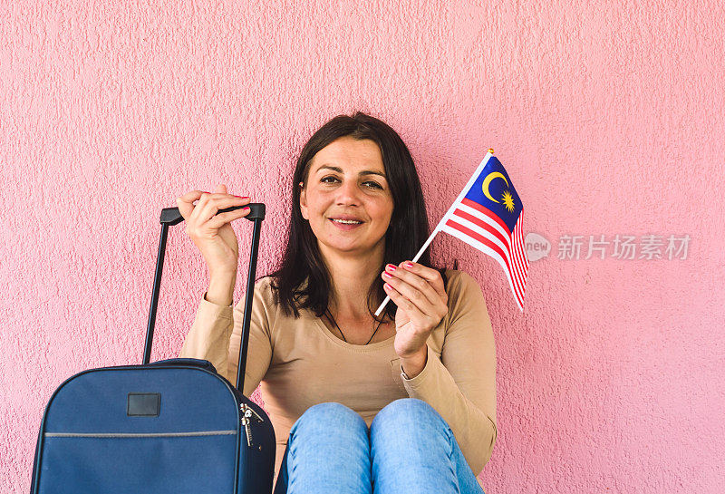 拿着旅行袋和马来西亚国旗的女人