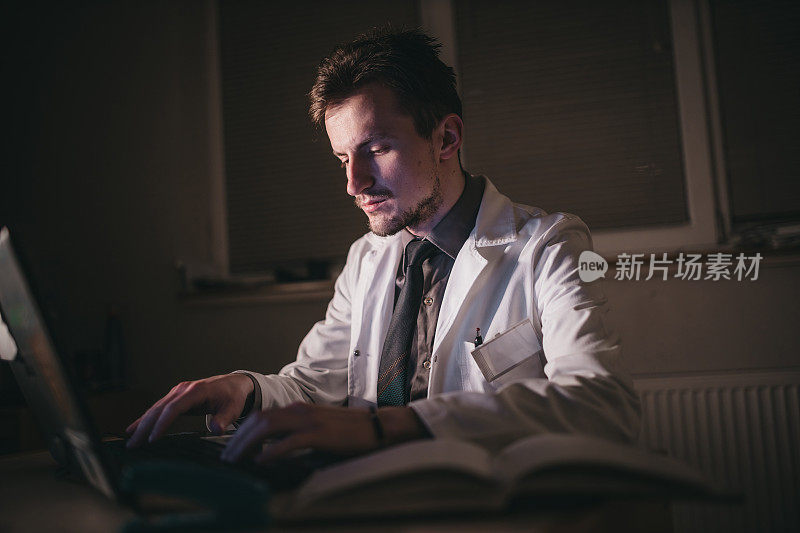 疲惫的年轻医生在他的办公室晚上工作