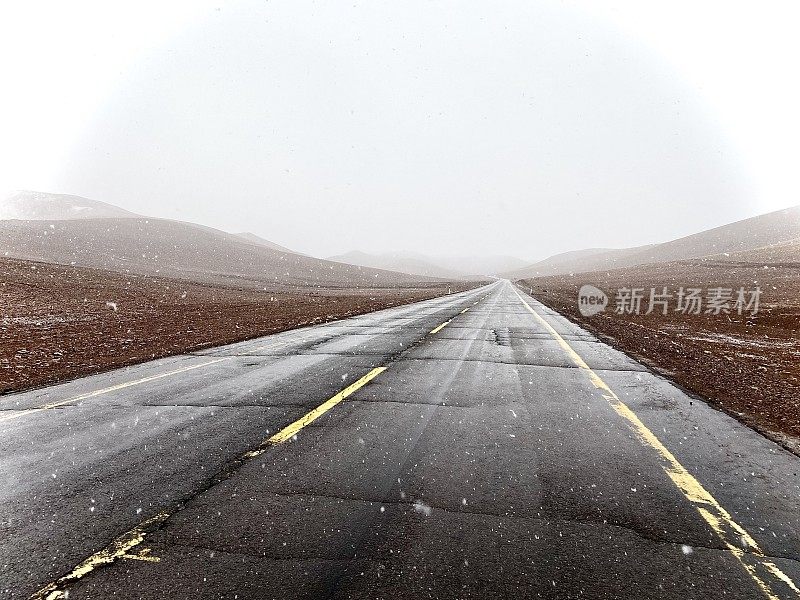 沙漠地区一条笔直的道路上正在下雪