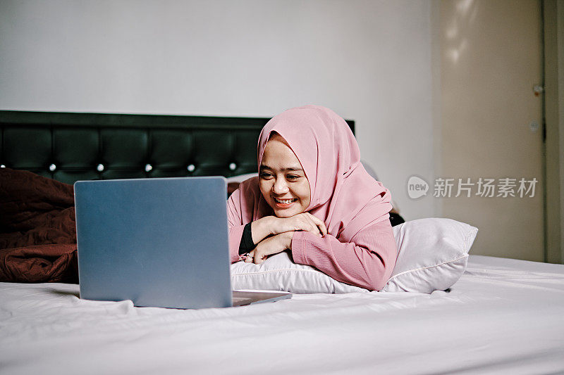 印尼妇女在床上用笔记本电脑进行视频通话